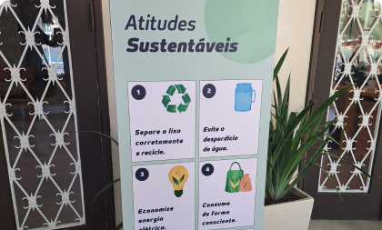 Totem informativo com o título 'Atitudes Sustentáveis' e quatro ilustrações numeradas sobre separação de lixo, economia de água, economia de energia e consumo consciente.